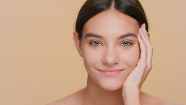 Young woman looks at camera and puts her cheek on her palm