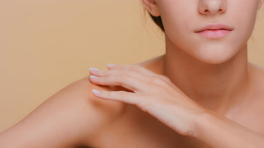 Beauty model gently touches her shoulder, clavicles and face