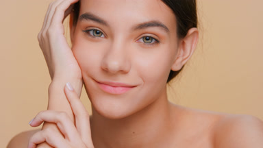Young woman runs her fingers along her arm and looks at camera