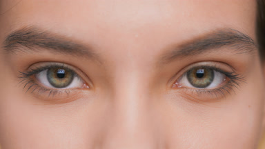 Young woman opens her eyes and looks at camera