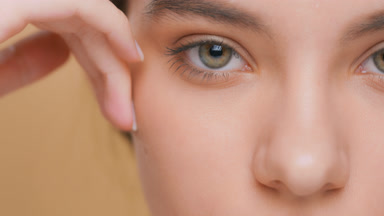 Extreme close-up beauty portrait of young woman touches her face
