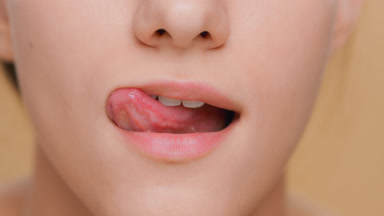 Detail shot of young woman licks her lips and smiles