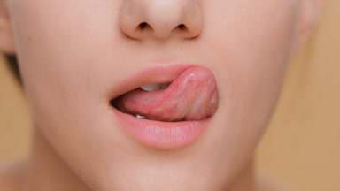 Detail shot of young woman licks her lips and makes a kiss