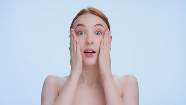 Shocked and surprised young ginger woman on blue background