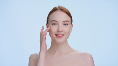 Young ginger woman touches her face from under the eye