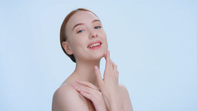 Ginger woman touches her face with pleasure on blue background