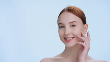Young ginger woman gently touches her face | place for product