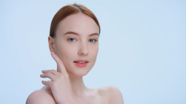 Ginger woman softly touches her face and shoulder