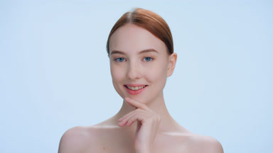 Young woman turns and looks at camera softly touching her face