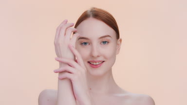 Young woman demonstrates softness of her hand skin on beige bg