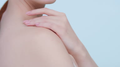 Young woman touches her shoulder, turns and looks at camera