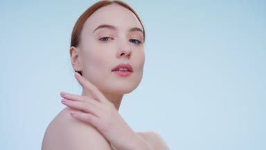 Low-angle beauty portrait of young ginger woman touches her body