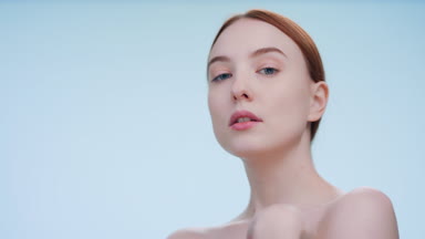 Low-angle portrait of young woman touch her body and looks away