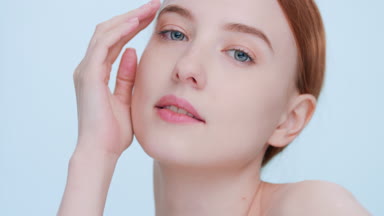 Young ginger woman touches her face and looks at camera close-up