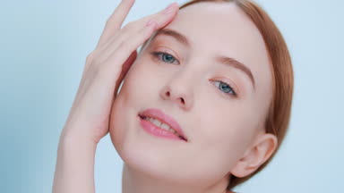 Closeup of young ginger woman with perfect skin touches her face