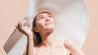 Young pretty woman in a white hat enjoys the sun smiling widely