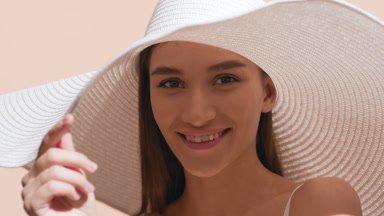 Young Caucasian woman in a big white hat smiles for the camera