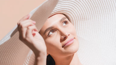 Young Caucasian woman in a big white hat smiles for the camera