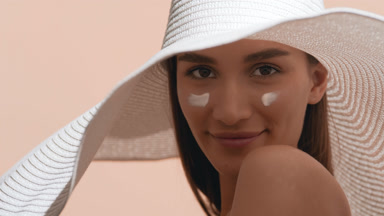 Woman with a smear of sunscreen on cheek applies it on another