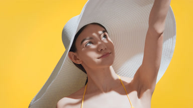 Girl in a white big hat covers her face from the sun with palm