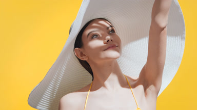 Girl covers face from the sun with her palm looking to the sky