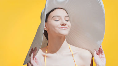 Young Caucasian woman in a big white hat enjoys the sun smiling