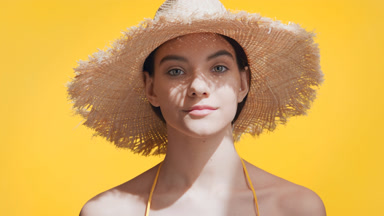 The sun comes out and woman in straw hat covers her face from it