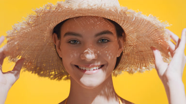 Young Caucasian woman puts a straw hat on her head smiling