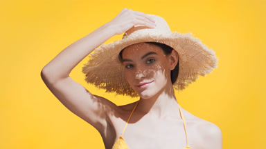 Young woman takes a straw hat off to use it like a hand fan