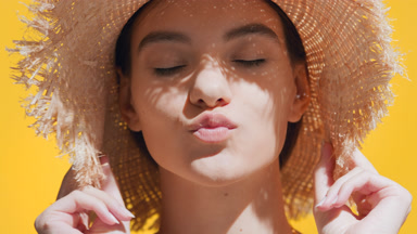 Young woman in a straw hat blows a kiss closing her eyes