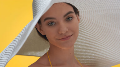 Young woman in a big white hat turns to the camera smiling