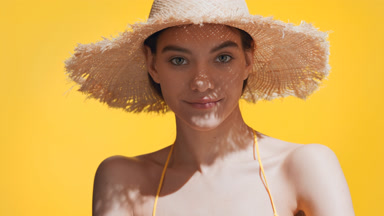 Woman in a hat puts sunblock on her shoulder and enjoys the sun