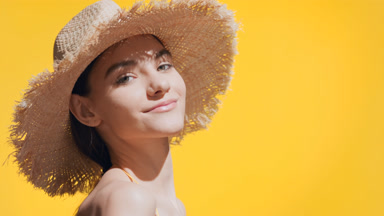 Woman in a hat puts sunscreen on her shoulder and enjoys the sun