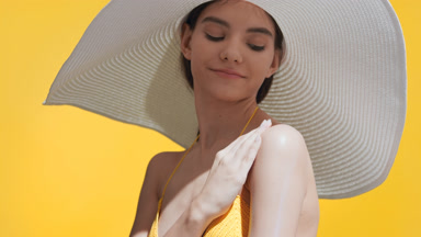 Woman applies sunscreen on shoulder and enjoys the sun smiling