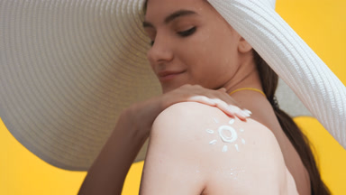 Woman applies spf cream on shoulder, turns and enjoys the sun