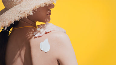 Woman puts sunscreen on her shoulder, enjoys the sun and smiles
