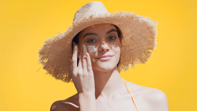Girl puts sunblock on her cheek, enjoys the sun and smiles