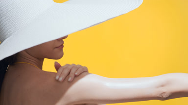 Woman with sunscreen on cheek and nose applies it on her hand