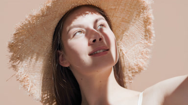 Woman covers face from the sun looking upward and turns back