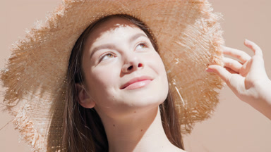 Girl in hat enjoys the sun looking upward and turns back smiling
