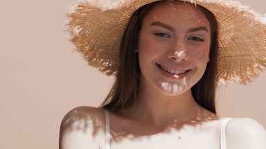 Woman in a hat enjoys the sun touching her shoulder and smiling