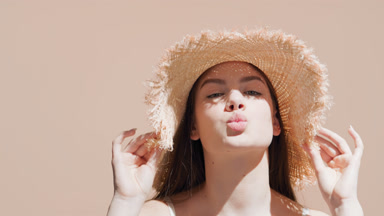 Young attractive European woman in a hat blows a kiss and smiles