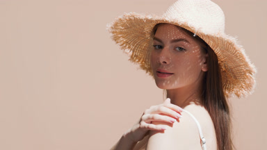 Young woman in a hat turns around touching shoulder and smiling