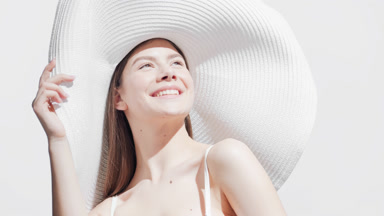 Woman in big white hat turns around enjoying the sun and smiling