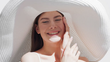 Young woman in a hat blows a kiss and smiles touching her face