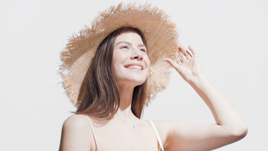 Woman in straw hat turns to the sun enjoying it and smiling wide