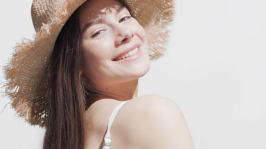 Woman in a hat turns back and forth enjoying the sun and smiling