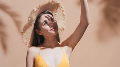Young woman covers her face from the sun with palm