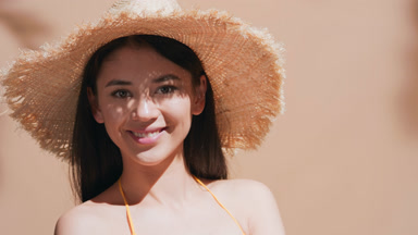 Young woman in the straw hat turns to the camera and smiles