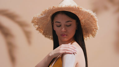 Young woman applying sunscreen on shoulder turns to the camera